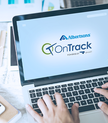 Close-up on laptop screen with OnTrack logo. Hand typing.