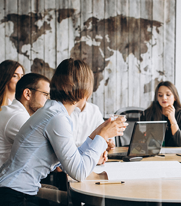 Team of employees seated at large conference table in office discussing